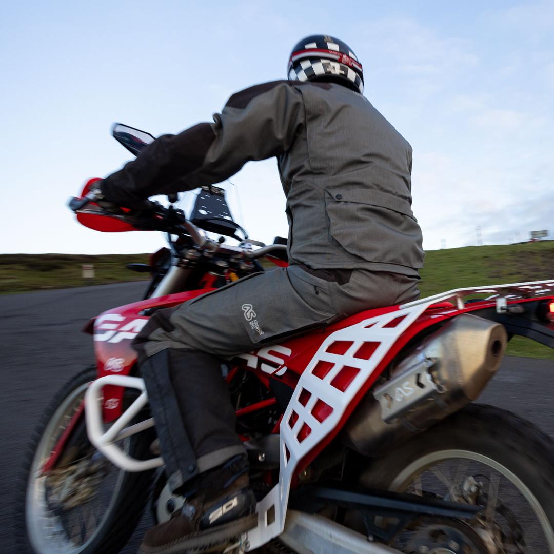 man riding red gasgas es 700 motorbike shot from behind with white luggage racks in the foreground