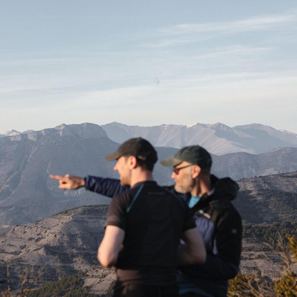 two men pointing to the distance in the mountains